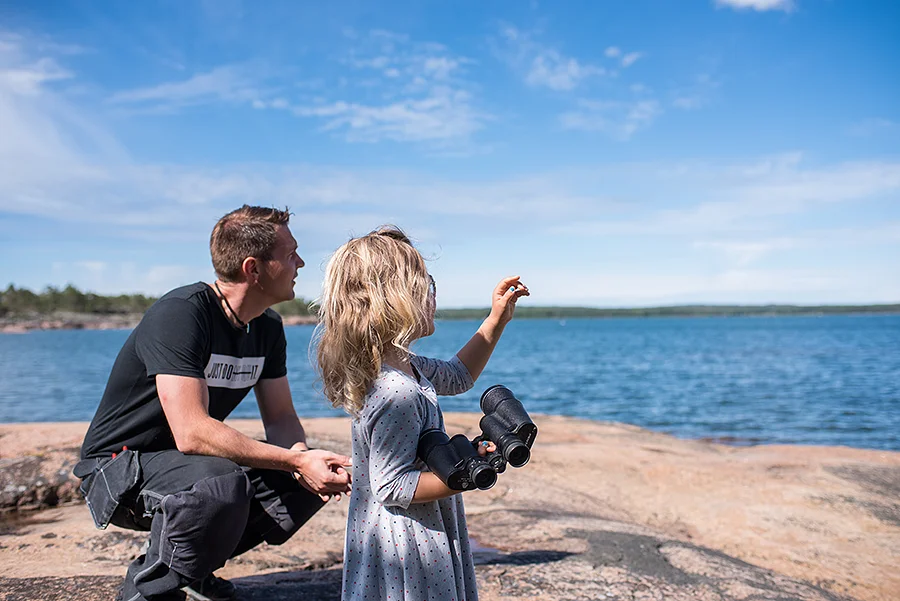 Pappa och barn tittar ut över Ålands hav med kikare.